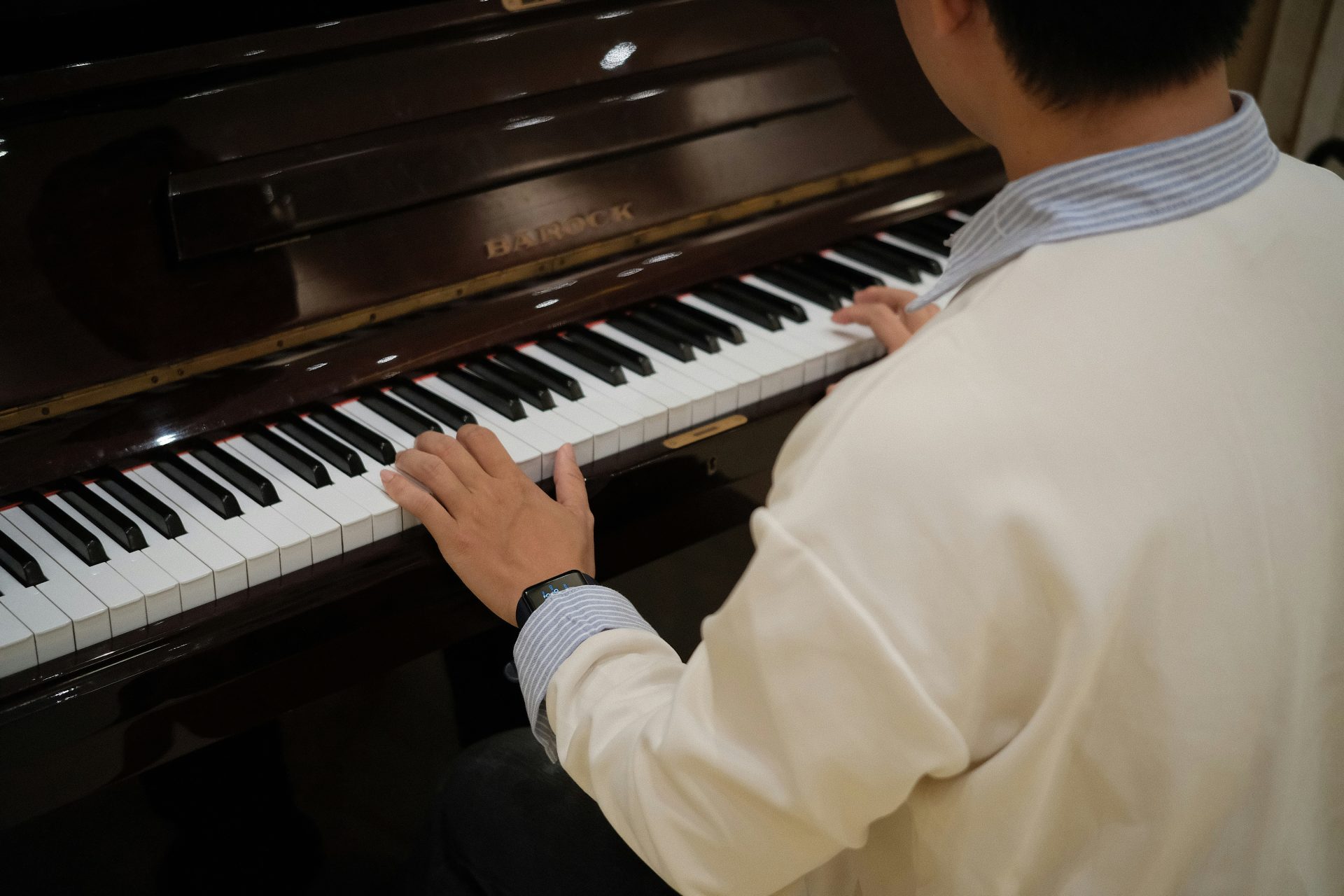 Person, die Klavier spielt und dabei die Hände auf den Tasten hat