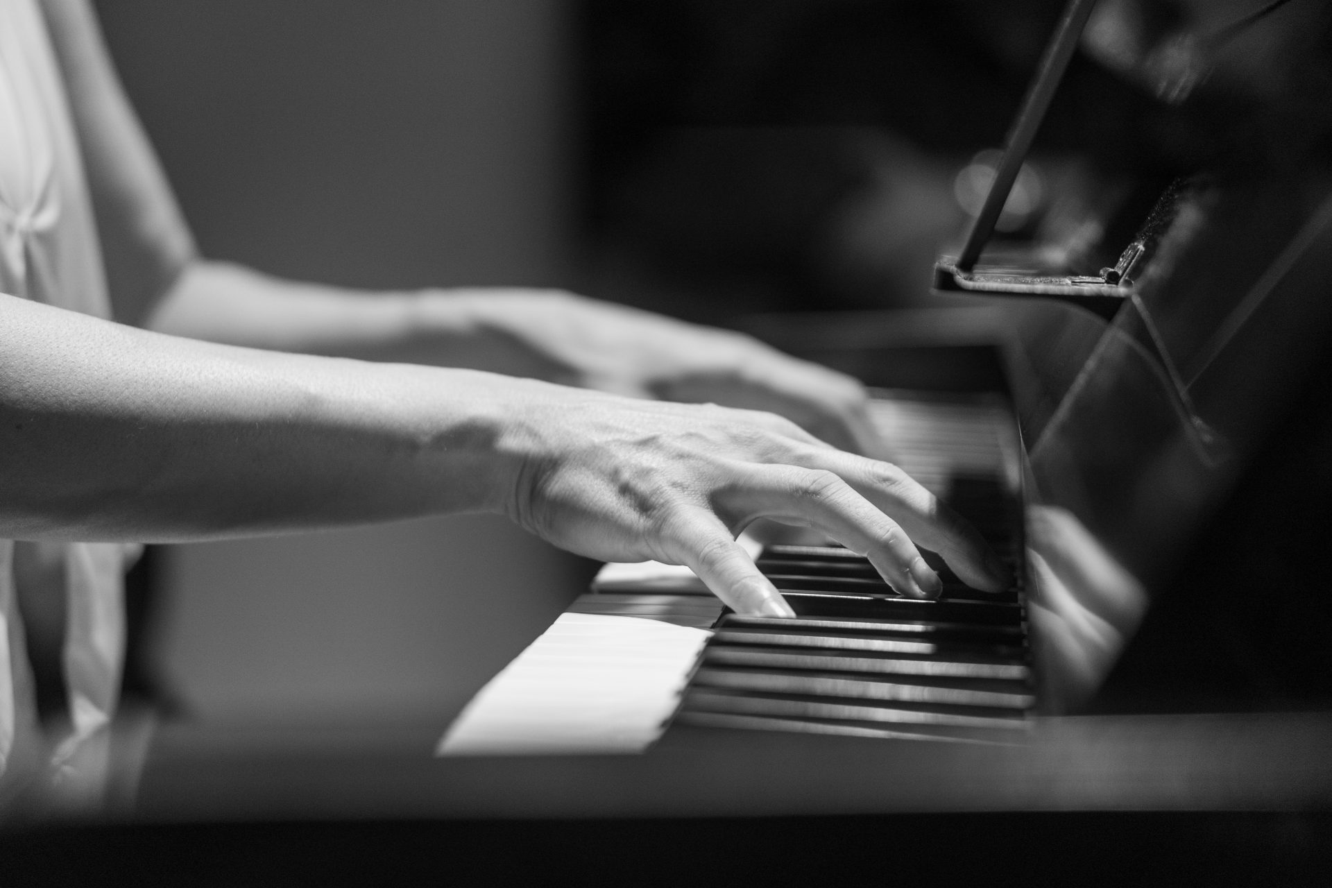 Eine Person, die auf einem Schwarzweißfoto Klavier spielt